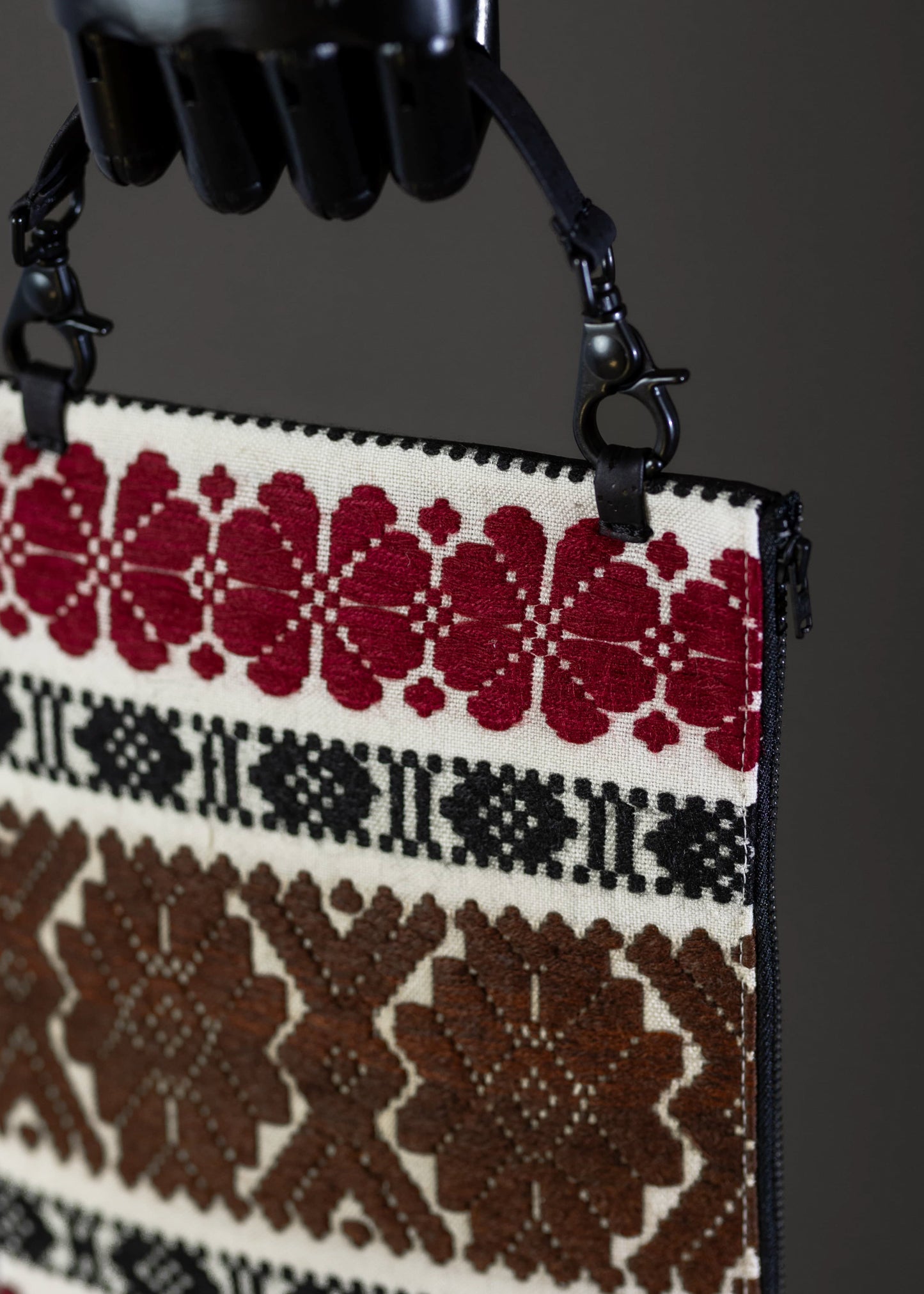 Detail of FTLO clutch showing the intricate traditional embroidery in earthy and red hues.