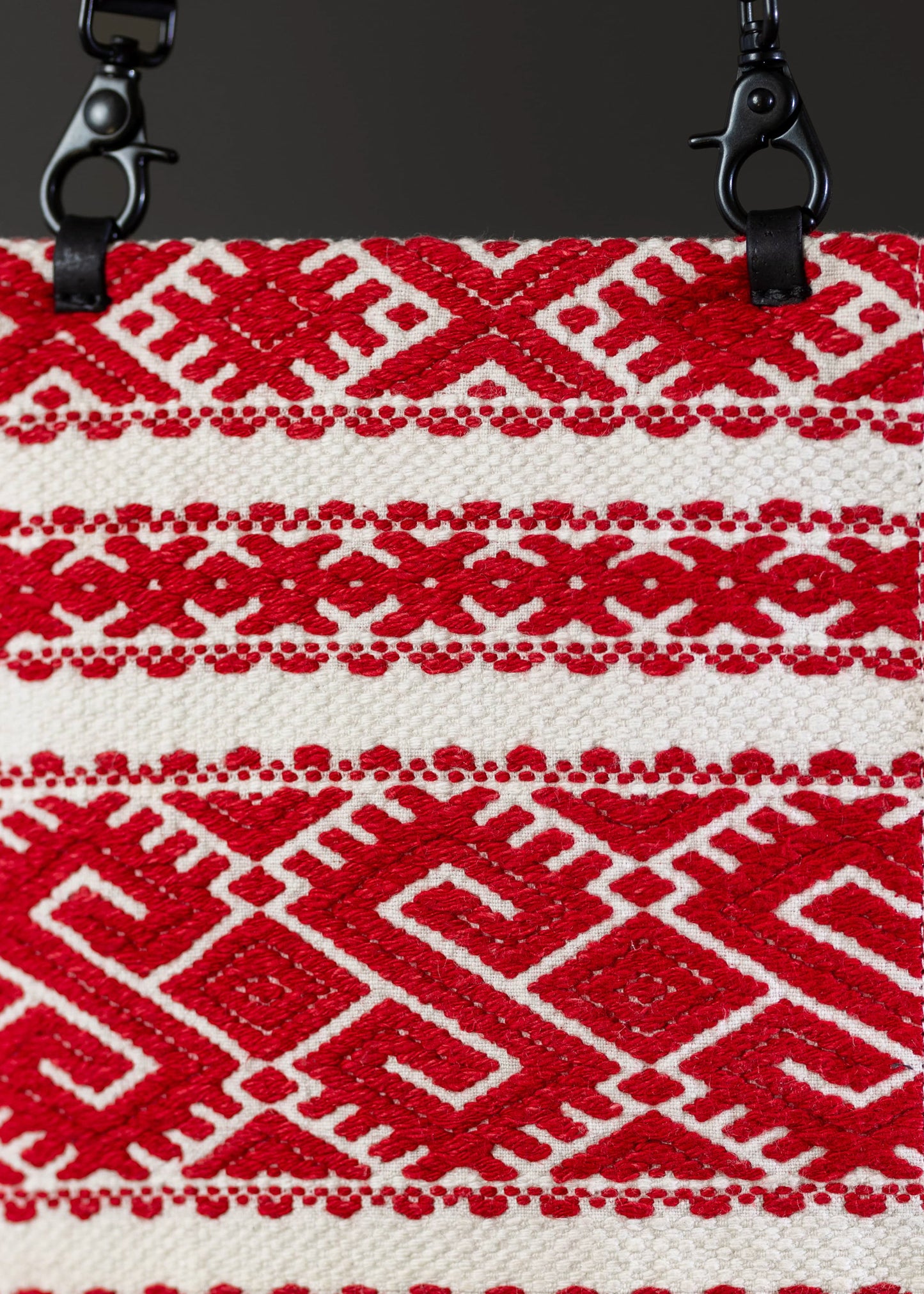 Close-up of the traditional geometric embroidery on FTLO's red and white Romanian handwoven bag.